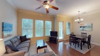 This single-floor residence offers a thoughtfully designed layout that balances comfort and functionality. The living area is a bright, welcoming space anchored by rich hardwood flooring, crown molding, and a ceiling fan overhead. Large windows flood the room with natural light and offer views of lush greenery outside, creating a serene indoor-outdoor connection. The living area flows seamlessly into a dedicated dining space, which features hardwood floors, a stylish chandelier, and direct access to an exterior door.

The kitchen is equipped with dark granite countertops, light wood cabinetry, a stainless steel sink, and tile flooring, providing both practical workspace and understated elegance. Crown molding continues throughout, lending a cohesive, polished character to the home.

The two bedrooms are carpeted for warmth and comfort, each featuring ceiling fans, crown molding, and windows that invite natural light. The primary bedroom includes direct access to an en-suite bathroom. Both bathrooms are finished with dark granite vanity countertops, warm wood cabinetry, tile flooring, and a combination tub and shower, with one bathroom also offering a separate walk-in shower. The overall ambiance is clean, comfortable, and move-in ready.