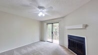 This single-floor residence offers a practical and efficient layout across two bedrooms and two bathrooms. The living area serves as the central gathering space, featuring soft carpet flooring, a ceiling fan with integrated lighting, a fireplace with a white mantel, and a sliding glass door that opens onto a balcony with outdoor views of surrounding greenery. Natural light flows in through the glass door, contributing to an open, airy feel.

The kitchen is positioned adjacent to the living area and features warm oak-toned cabinetry, dark countertops, wood-style flooring, and black appliances including a full-sized refrigerator. A pass-through design connects the kitchen to the living space, enhancing the overall flow.

Both bedrooms are carpeted and finished in neutral tones, with windows fitted with horizontal blinds allowing natural light and outdoor views. The spacious primary bedroom includes a ceiling fan and sliding glass door access to the balcony. The second bedroom is more compact but equally functional.

The two bathrooms each feature wood-style flooring, oak cabinetry, and full tub-shower combinations—one with white subway tile surround. Textured ceilings are consistent throughout, providing a cohesive aesthetic across the entire residence.