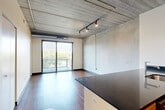 Located at 618 South Main Street in the heart of Ann Arbor, this one-bedroom, one-bathroom urban loft showcases an industrial-modern aesthetic throughout. The open-concept living and kitchen area serves as the centerpiece of the space, featuring striking exposed concrete ceilings with visible ductwork and track lighting that reinforce the loft's character. Rich hardwood flooring runs throughout the main living areas, complementing the kitchen's sleek dark granite countertops, warm wood cabinetry, stainless steel appliances, and a peninsula with an integrated sink — ideal for both cooking and entertaining. Floor-to-ceiling sliding glass doors flood the living area with natural light and provide access to a private balcony with lush outdoor views. The bedroom continues the industrial aesthetic with an exposed concrete ceiling, plush carpet flooring, a dedicated closet, and its own sliding glass door to the balcony, offering a serene retreat. The bathroom features matching wood cabinetry with dark granite countertops, a large vanity mirror, and hardwood-style flooring, maintaining design consistency across the unit. A dedicated closet provides additional storage. This well-appointed loft offers a compelling blend of urban industrial design and modern comfort in a prime Ann Arbor location.