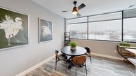Located at 1230 Elm St in Manchester, NH, this thoughtfully designed unit offers a well-appointed single-floor layout across four distinct areas. The open-concept kitchen is a standout feature, boasting crisp white shaker cabinetry, stainless steel appliances, a striking quartz waterfall peninsula with pendant lighting above, and bar seating for casual dining. Hardwood-style flooring runs throughout, lending warmth and continuity to the space.

The living and dining area is bathed in natural light thanks to expansive floor-to-ceiling windows that frame sweeping views of the Manchester cityscape. A ceiling fan adds comfort to this airy, inviting zone. The kitchen's integrated sink and peninsula flow seamlessly into this open living space, making it ideal for both everyday living and entertaining.

The bedroom offers a calm retreat with neutral gray walls, clean white trim, and well-proportioned dimensions that comfortably accommodate a full bed setup. The full bathroom features wood-look flooring, a white vanity, a tub-shower combination with matte black fixtures, and warm neutral tones that complete the polished, modern aesthetic found throughout the residence.