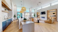 Bask Deer Valley, located at 26800 N 27th Ave in Phoenix, AZ, is a thoughtfully designed community facility spanning a generous single-floor footprint. The space makes an immediate impression with a polished reception area, where a sculptural marble-front desk is set against a bold geometric-patterned feature wall adorned with elegant pendant lighting and warm wood flooring throughout.

The soaring double-height living lounge is a standout centerpiece, flooded with natural light through expansive floor-to-ceiling glass windows that frame views of the surrounding palm-lined resort-style pool area. A white brick fireplace with built-in, backlit wood shelving anchors the room, complemented by a large wall-mounted TV, curated décor, and comfortable seating arrangements that invite relaxation and socializing.

The open-plan layout connects seamlessly to an outdoor patio, where a large dining table overlooks the shimmering pool and lush landscape — an ideal extension of the interior living space suited to Phoenix's sunny climate.

The fully equipped exercise room offers a comprehensive fitness experience, featuring cardio machines including treadmills and cycles, free weights, benches, and motivational wall typography. Large windows bring in natural light, maintaining an energizing atmosphere. Together, these spaces deliver a refined, resort-inspired environment for community living.