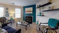 This single-floor residence at 3530 Brookstone Dr in Cincinnati offers a well-organized layout with distinct living spaces connected by wood-look flooring and neutral-toned walls throughout. The living room serves as a central gathering area, highlighted by a bold teal accent wall framing a fireplace with a sleek surround. Floating shelves add functional display space, while a window allows natural light to fill the carpeted room. Adjacent to the living area, the dining space features a sliding glass door that opens to a private balcony with outdoor seating, providing views of surrounding trees and bringing additional natural light into the space.

The galley-style kitchen is efficiently designed with light wood cabinetry lining both walls, dark countertops, and stainless steel appliances including a range and refrigerator. A pass-through leads to a dedicated laundry and utility area accented with a vibrant yellow wall.

The primary bedroom is generously proportioned with plush carpet, a window with soft draping, and ample room for furnishings. A second bedroom offers comfortable accommodations with natural light and carpeted flooring. Each bedroom is served by its own full bathroom, both featuring wood-look flooring, vanities with light cabinetry, and tub-shower combinations.