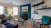 This single-floor residence at 3530 Brookstone Dr in Cincinnati offers a well-organized layout with distinct living spaces connected by wood-look flooring and neutral-toned walls throughout. The living room serves as a central gathering area, highlighted by a bold teal accent wall framing a fireplace with a sleek surround. Floating shelves add functional display space, while a window allows natural light to fill the carpeted room. Adjacent to the living area, the dining space features a sliding glass door that opens to a private balcony with outdoor seating, providing views of surrounding trees and bringing additional natural light into the space.

The galley-style kitchen is efficiently designed with light wood cabinetry lining both walls, dark countertops, and stainless steel appliances including a range and refrigerator. A pass-through leads to a dedicated laundry and utility area accented with a vibrant yellow wall.

The primary bedroom is generously proportioned with plush carpet, a window with soft draping, and ample room for furnishings. A second bedroom offers comfortable accommodations with natural light and carpeted flooring. Each bedroom is served by its own full bathroom, both featuring wood-look flooring, vanities with light cabinetry, and tub-shower combinations.
