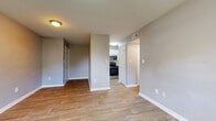 This single-floor residence offers a practical and comfortable layout with a neutral color palette of soft gray tones, white trim, and warm wood-look flooring throughout the main living areas. The open living and dining area is spacious and bright, with flush-mount ceiling lighting and a windowed entry door that allows natural light to fill the room. The kitchen is efficiently designed, featuring white shaker-style cabinetry, white quartz countertops, a classic subway tile backsplash, and a full suite of stainless steel appliances including an electric range, over-the-range microwave, and refrigerator. The bedrooms are carpeted for comfort and each includes a window with blinds offering views of greenery outside, providing a quiet and restful atmosphere. The two bathrooms are finished with white vanities, white quartz countertops, brushed nickel fixtures, and wood-look tile flooring. One bathroom includes a shower-tub combination. Throughout the space, textured ceilings, clean white baseboards, and consistent finishes contribute to a cohesive and well-maintained interior. The thoughtful floor plan connects each area seamlessly, making the overall space feel functional and move-in ready.