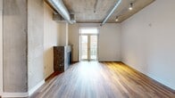 This contemporary 760 sq ft apartment in Denver showcases an industrial-chic aesthetic with modern amenities. The open-concept living area features exposed ductwork and concrete ceilings, creating an urban loft ambiance. Large windows flood the space with natural light and offer city views. The kitchen boasts honey-colored wood cabinetry, granite countertops, and stainless steel appliances, perfect for culinary enthusiasts. The primary bedroom, measuring 190 sq ft, provides ample space and includes a closet. Both bedrooms feature plush carpeting for comfort. The bathroom continues the modern theme with a granite vanity and sleek fixtures. Hardwood floors in the main living areas add warmth to the industrial design. In-unit laundry facilities offer convenience. The apartment's layout maximizes space efficiency, making it ideal for urban living. Its location at 2200 Market St puts residents in the heart of Denver's vibrant scene.