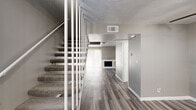 This two-story home offers a practical and well-organized layout across two floors, providing comfortable living spaces throughout. The main level features a living room highlighted by a built-in fireplace with a clean white surround, complemented by wood-look plank flooring in a warm gray tone that flows through the main areas. A staircase with white balusters and carpeted treads connects the two levels, adding a classic architectural touch to the interior.

The kitchen is a functional standout, featuring dark espresso cabinetry, granite-look countertops, a mosaic tile backsplash, stainless steel appliances, and a bright window that fills the space with natural light. Both bathrooms are finished with dark wood vanities, granite countertops, and wood-look tile flooring, with one bathroom offering a tub-shower combination accented by large-format tile surround.

The upper floor houses the three bedrooms, including a generously sized primary bedroom. The bedrooms feature neutral gray walls, plush carpeting, and windows that bring in natural light. A dedicated closet provides additional storage. The overall palette of soft grays and warm neutrals throughout the home creates a clean, cohesive, and move-in ready atmosphere.