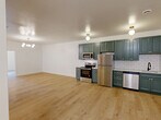 Located at 300 Benedict Dr in Pittsburgh, PA, this well-appointed 2-bedroom, 1-bathroom residence offers a thoughtfully designed single-floor layout with modern finishes throughout. Light hardwood flooring flows continuously across the entire space, creating a cohesive and airy feel.

The open-concept living, dining, and kitchen area serves as the heart of the home. The kitchen is a standout feature, showcasing deep teal shaker-style cabinetry with brass hardware, white subway tile backsplash, and a full suite of stainless steel appliances including a refrigerator, range, microwave, and dishwasher. Globe pendant and flush-mount brass light fixtures add a contemporary touch.

The two bedrooms are comfortably sized, with the primary bedroom featuring a mirrored sliding closet. An additional closet provides further storage. Each bedroom is bright and clean with crisp white walls and hardwood flooring.

The bathroom is elegantly finished with marble-look tile flooring, vertical linear wall tile, a green vanity with white countertop, gold-accented vanity lighting, and an arched mirror. A dedicated laundry area and an entrance complete the layout. The overall aesthetic is clean, modern, and move-in ready.