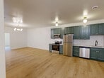 Located at 300 Benedict Dr in Pittsburgh, PA, this well-appointed 2-bedroom, 1-bathroom residence offers a thoughtfully designed single-floor layout with modern finishes throughout. Light hardwood flooring flows continuously across the entire space, creating a cohesive and airy feel.

The open-concept living, dining, and kitchen area serves as the heart of the home. The kitchen is a standout feature, showcasing deep teal shaker-style cabinetry with brass hardware, white subway tile backsplash, and a full suite of stainless steel appliances including a refrigerator, range, microwave, and dishwasher. Globe pendant and flush-mount brass light fixtures add a contemporary touch.

The two bedrooms are comfortably sized, with the primary bedroom featuring a mirrored sliding closet. An additional closet provides further storage. Each bedroom is bright and clean with crisp white walls and hardwood flooring.

The bathroom is elegantly finished with marble-look tile flooring, vertical linear wall tile, a green vanity with white countertop, gold-accented vanity lighting, and an arched mirror. A dedicated laundry area and an entrance complete the layout. The overall aesthetic is clean, modern, and move-in ready.