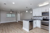 Located at 825 Powder Springs St in Marietta, GA, this single-floor space offers a clean, modern aesthetic with thoughtfully updated finishes throughout. The open-concept layout connects the kitchen and living area seamlessly, creating a bright and functional environment. Warm-toned luxury vinyl plank flooring extends throughout the entire space, providing a cohesive and durable foundation underfoot.

The kitchen is a standout feature, equipped with crisp white shaker-style cabinetry, dark quartz countertops, and a stone tile backsplash. A peninsula counter with pendant lighting above serves as both a workspace and a casual dining area. Stainless steel appliances—including a refrigerator, electric range, microwave, and dishwasher—complete the kitchen's modern, functional design. The adjacent living area is generously proportioned, featuring neutral gray walls and a ceiling fan with a brushed nickel finish.

The bedroom is a well-sized, private retreat, also fitted with a ceiling fan and continuing the same warm flooring as the rest of the unit. The bathroom features white shaker vanity cabinetry, a dark quartz countertop, a large frameless mirror, and a tiled tub-and-shower combination with marble-style wall tile and a built-in niche. The overall ambiance throughout the space is fresh, contemporary, and move-in ready.