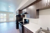 Located at 2709 Santa Maria Way in Santa Maria, California, this single-floor unit offers a well-designed layout across four functional areas. The living space is bright and open, featuring light wood-style flooring and two large windows fitted with horizontal blinds that allow generous natural light to fill the room. A built-in wall unit provides heating, and the clean, neutral walls contribute to an airy, welcoming atmosphere.

The kitchen is efficiently laid out and thoughtfully designed, showcasing rich dark wood cabinetry that extends to the ceiling for maximum storage. Black appliances — including a refrigerator, electric range with hood ventilation, and a built-in microwave — are seamlessly integrated alongside white countertops and a stainless steel sink, creating a sharp contrast that adds visual appeal.

The bathroom is spacious and accessibility-focused, featuring grab bars near the toilet and bathtub, a full tub, and light wood-style flooring that ties in with the rest of the unit. A dark wood shelving unit provides convenient storage within the bathroom. The closet area adjacent to the bathroom includes a hanging rod, offering practical wardrobe organization. Throughout the unit, the consistent use of light flooring, neutral tones, and dark cabinetry accents creates a cohesive and modern aesthetic.