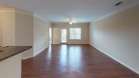 Located at 332 Carola Ln in Lexington, SC, this single-story residence offers a well-organized layout with a cohesive design throughout. The open-concept living and dining area is a standout feature, showcasing rich, dark wood-style flooring that runs throughout the main living spaces. Crown molding adds a refined architectural detail, while a ceiling fan with light kit provides both comfort and functionality. A glass-panel door allows natural light to filter into the living area, creating a bright and welcoming atmosphere.

The galley-style kitchen is equipped with dark espresso cabinetry, granite-style countertops, a stainless steel refrigerator, and a raised breakfast bar ideal for casual dining. Track lighting illuminates the kitchen corridor efficiently. The layout connects seamlessly to the main living and dining areas.

The bedrooms are finished with plush carpeting and feature ceiling fans, multiple windows for natural light, and access to walk-in closets, offering generous storage. One bedroom includes a dedicated walk-in closet with wire shelving.

The bathroom includes dark cabinetry with a granite-style vanity top, a vessel sink, wood-style flooring, and a shower-tub combination. A dedicated in-unit laundry area with washer and dryer hookups and overhead shelving adds everyday convenience to this well-appointed space.