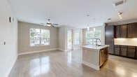 Located at 7490 Dwell Well Way in Winter Park, Florida, this single-floor residence offers a thoughtfully designed layout across two bedrooms and two bathrooms. The entry hallway welcomes you with light-toned tile flooring and a built-in mudroom nook with shelving, setting a clean, organized tone throughout.

The heart of the home is an open-concept living, dining, and kitchen area bathed in natural light from multiple large windows. The kitchen is a standout feature, showcasing rich dark-toned cabinetry with modern hardware, a white quartz countertop island with pendant lighting and an integrated sink, a subway tile backsplash, and a full suite of stainless steel appliances. A ceiling fan overhead and direct access to the patio complete this inviting shared space.

Both bedrooms feature plush carpeting and ceiling fans, with the primary bedroom offering a generously sized walk-in closet and a private en-suite bath. The primary bathroom includes a dual-sink vanity with quartz countertops, tile flooring, and a walk-in shower. The secondary bathroom features a tiled tub-shower combination and open built-in shelving. Additional conveniences include a dedicated laundry room and utility room.