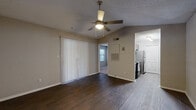 This efficiently designed 1-bedroom, 1-bathroom residence is laid out across a single floor, offering a practical and comfortable living arrangement. The living room serves as the central gathering space, featuring rich dark hardwood flooring, neutral warm-toned walls, and a ceiling fan with integrated lighting. Vertical blinds cover a sliding door that allows natural light to filter into the room, creating a bright and inviting atmosphere.

The galley-style kitchen is a functional highlight of the unit, equipped with stainless steel appliances including a refrigerator, microwave, and electric range. Dark espresso cabinetry is paired with granite countertops featuring subtle gray veining, offering both style and practicality. Wood-look flooring and recessed track lighting complete the kitchen's polished appearance.

The bedroom is carpeted for comfort and features a window with blinds that provides views of outdoor greenery, filling the room with soft natural light. A textured ceiling and neutral walls maintain the consistent, understated aesthetic found throughout the space. The bedroom also includes access to a dedicated walk-in closet outfitted with wire shelving and hanging rods, offering generous storage capacity.

The unit's layout connects each room efficiently, with consistent neutral tones and practical finishes throughout, making it a well-organized and functional living space.