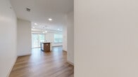 Located at 2967 Route 9W in Saugerties, NY, this single-floor unit showcases a clean, contemporary design with a bright, open-concept layout that seamlessly connects the main living areas. The space is anchored by a well-appointed kitchen featuring light wood cabinetry extending to the ceiling, stainless steel appliances including a refrigerator, range, and microwave, and a central island with a quartz countertop and built-in sink. Pendant globe lighting adds a modern touch overhead, while a sliding glass door floods the kitchen and living area with natural light and provides access to an outdoor deck.

The open living and dining area extends naturally from the kitchen, finished with warm-toned hardwood-style flooring that runs throughout the main spaces. Recessed lighting keeps the area bright and inviting. The bedroom features plush gray carpeting and crisp white walls, creating a calm, comfortable retreat. The bathroom is finished with hardwood-style flooring and includes a soaking tub with shower, clean white fixtures, and brushed nickel hardware. Throughout the unit, neutral white walls and consistent finishes create a cohesive, modern aesthetic well-suited to a variety of furnishing styles.