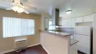 This single-floor residence offers a well-organized layout with a blend of functional design and comfortable living spaces. The open living area greets visitors with rich, dark hardwood-style flooring, neutral-toned walls, a textured ceiling, and a ceiling fan overhead. A large window allows generous natural light to fill the room, while a welcoming front door with a semicircular transom window adds character to the entry.

The kitchen is a standout feature, designed with a peninsula-style breakfast bar topped with granite-look countertops, providing both prep space and casual seating. White cabinetry lines the walls, complemented by a striking stainless steel island range hood as a focal point. The kitchen is fully equipped with a white electric range, dishwasher, and refrigerator, alongside a double-basin sink positioned beneath a window. Dark hardwood-style flooring continues throughout.

The bedrooms are finished with plush, light-colored carpeting and feature multiple windows fitted with vertical blinds, allowing for adjustable natural light while maintaining privacy.

The bathroom is finished with large-format dark stone-look tile that extends floor to ceiling around the tub surround, paired with a combination tub and shower and a window for ventilation. The overall ambiance of the space is clean, neutral, and move-in ready.
