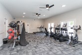 Located at 3822 Mizell Rd in Greensboro, NC, this fitness center is a well-appointed, single-floor facility designed to support a wide range of workout routines. The space is generously sized, offering an open layout that comfortably accommodates multiple exercise zones without feeling crowded.

The flooring throughout consists of patterned, multi-tone carpet tiles that provide both comfort and durability underfoot. Recessed lighting and ceiling fans are installed throughout, ensuring the space remains well-lit and well-ventilated during workouts.

Along one side of the facility, a row of cardio equipment — including treadmills, elliptical trainers, and stationary bikes — faces a wall of large French doors and windows that open to views of an outdoor pool area, flooding the space with natural light and providing a refreshing outdoor connection.

The strength training section is equally comprehensive, featuring a cable machine, a Smith machine with a weight bench, a full dumbbell rack with a wide range of weights, and a dedicated functional training station equipped with resistance bands, medicine balls, stability balls, and kettlebells. A curved slant board rounds out the functional fitness options.

The walls are finished in neutral tones with chair-rail detailing, contributing to a clean, polished aesthetic. The overall ambiance is bright, airy, and motivating — a professional-grade fitness environment suited for residents of all fitness levels.