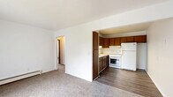Located at 207 Water Street in Brooklyn, Michigan, this single-floor, 3-bedroom, 1-bathroom unit offers a practical and efficiently arranged layout. The living room serves as the welcoming centerpiece of the home, featuring neutral carpet flooring, white walls, and a large sliding glass door dressed with vertical blinds that fills the space with natural light and provides outdoor views. A wall-mounted air conditioning unit and baseboard heaters ensure year-round comfort. The kitchen is directly accessible from the living area and is equipped with rich, dark wood cabinetry — both upper and lower — offering ample storage. It features a double stainless steel sink, light-toned countertops, a white electric range, and a full-size refrigerator, all set on durable hardwood-style flooring. A hallway connects the living spaces to the three bedrooms, each finished with neutral carpet, white walls, and individual windows with blinds for natural light and privacy. The primary bedroom includes a built-in closet with bi-fold wood doors and baseboard heating. The bathroom features a clean, white tub and shower surround. This unit presents a straightforward, low-maintenance interior well-suited for comfortable everyday living.
