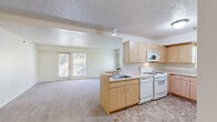 Located at 6749 Tall Oaks Dr in Kalamazoo, MI, this single-floor, one-bedroom, one-bathroom unit offers a practical and comfortable layout designed for efficient living. The open-concept kitchen and living area forms the heart of the unit, where light maple cabinetry, white appliances including a gas range and built-in microwave, and a peninsula with an integrated sink provide a functional and well-equipped cooking space. Tile flooring grounds the kitchen zone, which flows seamlessly into the carpeted living area — a bright, open space that benefits from natural light admitted through double doors and multiple windows offering views of surrounding greenery. The bedroom is generously sized, featuring plush carpeting, a large window framing leafy outdoor views, and access to a well-organized walk-in closet outfitted with wire shelving and basket storage for ample organization. The bathroom features tile flooring, a window for natural ventilation, and clean, neutral finishes. A hallway connects the living spaces and includes additional storage access. Throughout the unit, textured ceilings, neutral warm-white walls, and soft carpeting create a cohesive, understated ambiance suited to a range of personal styles.