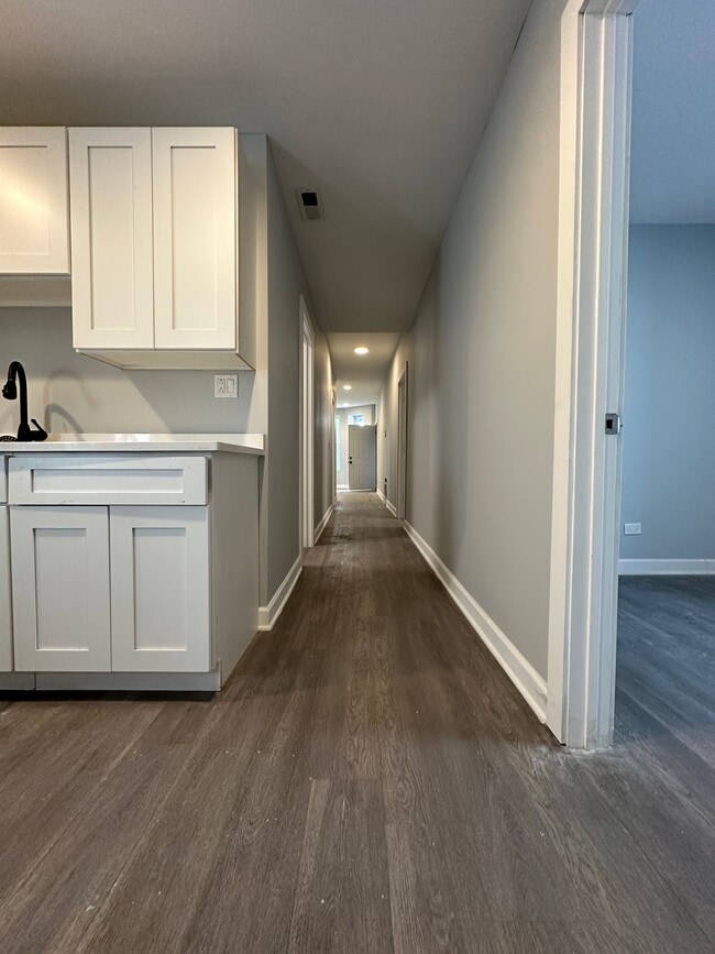 Renovated kitchen with white cabinetry and a view down the hallway - 5653 S May St