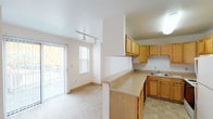 This three-floor residence offers a practical and well-organized layout spread across multiple levels. The kitchen is a standout functional space, featuring warm honey-toned wood cabinetry arranged in a U-shaped configuration that maximizes storage and counter space. Fitted with a stainless steel sink, electric range, refrigerator, and dishwasher, the kitchen also includes a pass-through counter that connects to the adjacent living area. Tile flooring grounds the kitchen, while the living area transitions to soft wall-to-wall carpeting underfoot.

The living room benefits from a sliding glass door that opens onto a balcony, allowing natural light to fill the space alongside an additional window. Track lighting runs along the ceiling, providing flexible illumination throughout. Multiple bedrooms are distributed across the floors, each carpeted and finished with neutral white walls and windows that frame views of surrounding greenery. The bedrooms are well-proportioned, offering comfortable living space with good natural light.

The bathrooms are clean and simply appointed, featuring white square-tile surrounds in the tub-shower combinations, tile flooring, and wood-toned vanities. Throughout the residence, the overall aesthetic is understated and neutral, providing a versatile backdrop well-suited to personalization.