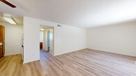 Located at 1206 W Fourth St, Unit 15, in Ontario, California, this single-floor apartment offers a clean, functional layout with a bright and open interior. The living area is spacious and filled with natural light streaming through large windows fitted with vertical blinds. Light wood-style laminate flooring runs throughout the entire unit, creating a cohesive and easy-to-maintain surface. A wall-mounted air conditioning unit provides climate control in the main living space, which also features a ceiling fan for added comfort. The front entry opens directly into this airy living area. A galley-style kitchen lines both walls with warm wood cabinetry, granite-style countertops, and white appliances including a gas range, refrigerator, and dishwasher, along with a double-basin sink. The hallway connects the living spaces to the bedroom and bathroom, with a thermostat conveniently mounted on the wall. The bedroom is generously sized with a wide window that allows ample natural light. The bathroom features warm wood cabinetry with a granite-style countertop, a framed mirror, a small window for ventilation, and a separate bathtub and shower area. The unit presents a clean, move-in-ready condition throughout.