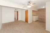 Located at 22 US Highway 60 in Canyon, TX, this single-floor unit offers a straightforward and functional layout. The living area is finished with wall-to-wall carpet and features a ceiling fan with light fixture, providing comfortable airflow. A distinctive exposed brick accent wall adds character to the open area connecting the living space to the kitchen, creating a warm, textured visual contrast against the neutral painted walls.

The kitchen is equipped with white cabinetry featuring black hardware, a double-basin stainless steel sink, a coil-element electric range, and white tile backsplash. A peninsula or countertop divider partially separates the kitchen from the living area, contributing to an open yet defined floor plan. Tile flooring runs through the kitchen for easy maintenance.

The bedroom is carpeted and includes a ceiling fan, a window fitted with blinds for natural light and privacy, and a textured ceiling. The bathroom features a full tub and shower combination with white square tile surround, a chrome grab bar, tile flooring, and clean white walls.

Throughout the unit, ceiling fans are present in the main rooms, and windows with blinds allow for natural light while maintaining privacy. The overall layout is compact and efficient, making practical use of the available space on a single level.