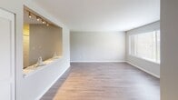 Located at 1534 N Rand Rd in Palatine, Illinois, this single-floor residence offers a well-designed layout with contemporary finishes throughout. The kitchen is outfitted with stainless steel appliances, including a range, over-the-range microwave, and dishwasher, complemented by crisp white cabinetry, light countertops, and a stainless steel sink. The cabinetry extends to the upper walls, providing ample storage space in a clean, modern aesthetic.

The living area is generously proportioned, featuring hardwood-style flooring in a warm neutral tone that runs throughout the main living spaces. Large windows with blinds allow abundant natural light to fill the room, offering views of the surrounding greenery and parking area. A pass-through ledge with track lighting connects the kitchen and living areas, adding both functionality and visual interest to the open layout.

The bathroom is neatly appointed with a white vanity, light countertop, and a well-lit mirror flanked by modern fixtures. A tiled tub and shower combination with a decorative curtain completes the space. Overall, the unit presents a clean, contemporary atmosphere suitable for comfortable everyday living.