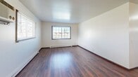 This 2-bedroom, 1-bathroom unit in Fond du Lac, Wisconsin offers a straightforward, functional layout across a single floor. The living room greets you at the entry, featuring rich hardwood-style flooring, a wall-mounted air conditioning unit, and a large window that draws in natural light and outdoor views. Baseboard heating is present throughout the unit, ensuring comfort year-round.

The galley-style kitchen is well-appointed with white cabinetry lining both walls, providing ample storage, along with white appliances including a range and refrigerator, and a stainless steel sink. An adjacent pantry offers additional storage space.

Both bedrooms are carpeted and feature natural light from large windows with views of the surrounding area. Each bedroom includes a sliding-door closet, offering practical storage. The primary bedroom is a comfortable size with room for standard furnishings.

The bathroom is cleanly finished with a wide vanity topped in white, updated gray cabinetry, a large framed mirror with modern light fixtures above, and a tiled tub-shower combination. The hardwood-style flooring continues into the bathroom, tying the space together cohesively. This unit provides an efficient and comfortable living environment in a residential Fond du Lac neighborhood.