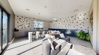 Located at 1100 West Temple Street in Los Angeles, this thoughtfully designed amenity lounge offers a cohesive blend of modern aesthetics and functional comfort across a single floor. The space is immediately distinguished by its bold geometric tile work — a striking black-and-white triangular mosaic pattern that wraps across the walls, creating a dynamic visual backdrop throughout.

The kitchen area serves as a central focal point, featuring sleek gray cabinetry, a substantial granite-topped island with bar seating, and pendant lighting that adds warmth and depth. Full-length windows alongside the kitchen draw in generous natural light while framing views of the surrounding Los Angeles cityscape.

Adjacent to the kitchen, a dining area provides an intimate setting for gathering, complemented by the deep navy tile accent wall that adds a sophisticated contrast to the lighter tones elsewhere. The lounge area is furnished with plush gray sofas and stylish accent chairs with distinctive yellow-accented frames, arranged around a media console and wall-mounted display.

A slatted wood partition wall adds architectural texture, subtly dividing the lounge zones while maintaining an open, airy feel. Large-format light tile flooring runs seamlessly throughout, unifying the space. Sliding glass doors open directly onto an outdoor terrace, extending the usable area and offering additional seating with open-air city views — a standout feature of this vibrant urban retreat.