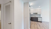 Located on Westwood Boulevard in the heart of Los Angeles, this modern single-floor unit offers a clean, contemporary design throughout. Wood-style plank flooring runs continuously across the open living and dining area, which is bathed in natural light from large windows and a glass door leading to a private balcony with views of the surrounding neighborhood and city skyline.

The well-appointed kitchen features stainless steel appliances, including a French door refrigerator, range, microwave, and dishwasher. Two-tone cabinetry combines white upper cabinets with dark wood lower cabinets, complemented by a neutral tile backsplash and sleek countertops, creating a functional and stylish cooking space.

The unit includes two generously sized bedrooms, each with wood-style flooring, sliding closet doors, and built-in shelving for organized storage. One bedroom benefits from a window offering views of palm trees and the cityscape beyond.

Two full bathrooms serve the unit, both finished with large-format tile flooring, white subway tile tub surrounds, dark wood vanities with white countertops, backlit mirrors, and matte black hardware and fixtures. The overall aesthetic is consistently modern and understated, with crisp white walls and recessed lighting throughout.