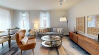 This single-floor, two-bedroom, two-bathroom residence presents a thoughtfully designed layout with contemporary finishes throughout. The living room features neutral gray walls, wood-look flooring, and multiple windows dressed with sheer white curtains that allow generous natural light to fill the space, creating a bright and welcoming atmosphere.

The kitchen is outfitted with a two-tone cabinet design—crisp white upper cabinets contrasting with dark lower cabinets—paired with light quartz countertops and a full suite of stainless steel appliances, including a gas range, built-in microwave, dishwasher, and refrigerator. A window above the sink provides additional natural light and outdoor views.

Both bedrooms are carpeted and well-proportioned. The primary bedroom features large sliding glass doors opening to an outdoor area, while the second bedroom also benefits from exterior-facing windows with views of a slatted wood privacy screen. Each bedroom includes a dedicated closet for ample storage.

The two bathrooms maintain a consistent modern aesthetic, featuring dark-stained vanities with white countertops, large mirrors, and tile flooring. The primary bath includes a glass-enclosed walk-in shower with subway tile surround, while the second bath offers a similarly clean, functional design. Wood-look flooring flows through the main living areas, tying the overall space together cohesively.