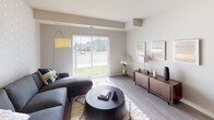 This single-floor residence offers a thoughtfully laid-out living space with a cohesive contemporary design throughout. The kitchen is a standout feature, showcasing rich dark-stained cabinetry with sleek hardware, light quartz countertops, a classic white subway tile backsplash, and a full suite of stainless steel appliances including a range, microwave, dishwasher, and refrigerator. A kitchen island provides additional prep and casual dining space, while wood-look flooring grounds the area with warmth and durability.

The open living area flows naturally from the kitchen, featuring the same wood-look flooring and large sliding glass doors that flood the room with natural light and offer views of the surrounding greenery. An accent wall with a subtle geometric pattern adds visual interest without overwhelming the neutral palette.

The bedroom is carpeted for comfort and includes a well-sized window that brings in natural light. It connects directly to a bathroom with dark cabinetry matching the kitchen, a white quartz vanity, an undermount sink with brushed nickel fixtures, and a large frameless mirror. A closet is accessible from the bathroom area, adding practical storage. The overall ambiance is modern, clean, and cohesive.