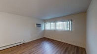 This single-floor, two-bedroom, one-bathroom residence in Michigan City, Indiana offers a clean, updated interior designed for comfortable everyday living. The layout flows logically between living, sleeping, and functional spaces, all unified by wood-style vinyl plank flooring that runs throughout the unit.

The living area is spacious and well-lit, featuring large windows with vertical blinds that allow generous natural light. A wall-mounted air conditioning unit and baseboard heating provide year-round climate control. The room offers ample space for a variety of furniture arrangements.

The kitchen is thoughtfully appointed with crisp white shaker-style cabinetry extending to the ceiling, light countertops, and a full suite of stainless steel appliances including a refrigerator, dishwasher, and range. An under-cabinet range hood and a stainless sink add practical functionality to the space.

Both bedrooms are comfortably sized, each featuring vertical-blind-covered windows, ceiling fans with light fixtures, and baseboard heating. One bedroom includes a closet with built-in shelving. The shared bathroom is neatly finished with a white vanity, a tiled tub-shower combination, and brushed nickel fixtures, all set on matching vinyl plank flooring.