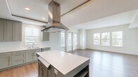 Located at 10501 Lakeline Mall Dr in Austin, TX, this thoughtfully designed 3-bedroom, 4-bathroom single-floor home offers a well-organized layout with modern finishes throughout. The open-concept kitchen and living area serves as the heart of the home, featuring sage-green cabinetry, a large central island with a white quartz countertop, a stainless steel island range hood, built-in appliances, and a dedicated workspace with additional cabinetry. The living area extends naturally from the kitchen, bathed in natural light from multiple large windows. Warm hardwood-style flooring runs consistently throughout the main living spaces and bedrooms, contributing to a cohesive and inviting aesthetic. The primary bedroom offers a comfortable footprint with a bank of triple windows overlooking the outdoors, along with a dedicated walk-in closet equipped with dual hanging rods and shelving. Additional bedrooms are bright and well-proportioned, each with access to natural light. The four bathrooms are cleanly finished, with at least one featuring a soaking tub and shower combo lined in white subway tile set in a herringbone pattern, complemented by marble-style tile flooring. A hallway and two closets provide practical storage throughout the home.