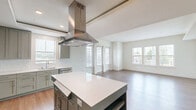 Located at 10501 Lakeline Mall Dr in Austin, TX, this thoughtfully designed 3-bedroom, 4-bathroom single-floor home offers a well-organized layout with modern finishes throughout. The open-concept kitchen and living area serves as the heart of the home, featuring sage-green cabinetry, a large central island with a white quartz countertop, a stainless steel island range hood, built-in appliances, and a dedicated workspace with additional cabinetry. The living area extends naturally from the kitchen, bathed in natural light from multiple large windows. Warm hardwood-style flooring runs consistently throughout the main living spaces and bedrooms, contributing to a cohesive and inviting aesthetic. The primary bedroom offers a comfortable footprint with a bank of triple windows overlooking the outdoors, along with a dedicated walk-in closet equipped with dual hanging rods and shelving. Additional bedrooms are bright and well-proportioned, each with access to natural light. The four bathrooms are cleanly finished, with at least one featuring a soaking tub and shower combo lined in white subway tile set in a herringbone pattern, complemented by marble-style tile flooring. A hallway and two closets provide practical storage throughout the home.
