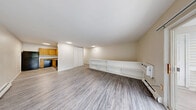 Located at 11 Farnsworth Dr in Slingerlands, NY, this one-bedroom, one-bathroom unit offers a practical and comfortable single-floor layout. The living room is bright and open, featuring durable wood-look vinyl flooring, a baseboard heating system, and a sliding glass door that opens to a private balcony with outdoor views of surrounding greenery, allowing natural light to fill the space. Adjacent to the living area, the kitchen is efficiently designed with warm oak cabinetry, granite-style countertops, a double sink, and black appliances including a refrigerator, electric range, dishwasher, and a range hood. A built-in shelving unit along one wall adds functional storage and display space, complemented by a closet and vinyl plank flooring. The generously sized primary bedroom is carpeted for comfort and features a large sliding closet, vertical blinds on the windows, and a baseboard heater, creating a quiet and cozy retreat. The full bathroom is finished with wood-paneled wainscoting, warm honey-toned wood vanity cabinetry with a white countertop, a bathtub, and wood-look vinyl flooring, giving it a clean and classic look. Throughout the unit, neutral tones create a cohesive and move-in-ready aesthetic.