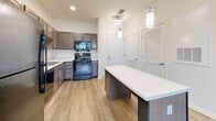 Located at 1410 Candle Light Blvd in Brooksville, Florida, this single-story one-bedroom, one-bathroom unit offers an efficiently designed layout across a compact yet functional footprint. The space is organized to maximize usability, with each room flowing logically into the next.

The kitchen is a standout feature, equipped with dark taupe shaker-style cabinetry, light quartz countertops, and a full suite of black appliances including a refrigerator, range, dishwasher, and built-in microwave. A central island with a white countertop provides additional workspace and casual dining potential. Wood-look flooring and pendant lighting lend a modern, polished feel to the area. A louvered-door closet nearby offers additional storage.

The bedroom is a comfortably sized room finished with soft wall-to-wall carpeting, a ceiling fan, and a window that allows natural light and views of the surrounding greenery. A dedicated closet serves the bedroom for organized storage.

The bathroom features wood-look tile flooring, a wide vanity with quartz countertops and dark cabinetry, a large mirror, and a tiled walk-in shower equipped with a grab bar. The clean, neutral palette throughout creates a cohesive and inviting atmosphere across the entire unit.
