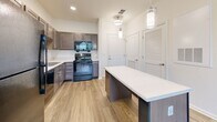 Located at 1410 Candle Light Blvd in Brooksville, Florida, this single-story one-bedroom, one-bathroom unit offers an efficiently designed layout across a compact yet functional footprint. The space is organized to maximize usability, with each room flowing logically into the next.

The kitchen is a standout feature, equipped with dark taupe shaker-style cabinetry, light quartz countertops, and a full suite of black appliances including a refrigerator, range, dishwasher, and built-in microwave. A central island with a white countertop provides additional workspace and casual dining potential. Wood-look flooring and pendant lighting lend a modern, polished feel to the area. A louvered-door closet nearby offers additional storage.

The bedroom is a comfortably sized room finished with soft wall-to-wall carpeting, a ceiling fan, and a window that allows natural light and views of the surrounding greenery. A dedicated closet serves the bedroom for organized storage.

The bathroom features wood-look tile flooring, a wide vanity with quartz countertops and dark cabinetry, a large mirror, and a tiled walk-in shower equipped with a grab bar. The clean, neutral palette throughout creates a cohesive and inviting atmosphere across the entire unit.