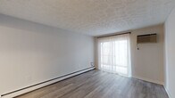 Located on Madison Road in Cincinnati, Ohio, this single-floor unit offers a clean, updated interior with a neutral palette and modern finishes throughout. The living area is a standout space, featuring smooth wood-style flooring in a warm gray tone, a patterned textured ceiling, and a full-width sliding glass door dressed with sheer white curtains. The door allows generous natural light to fill the room and provides direct access to the outdoors. Baseboard heating runs along the perimeter walls, ensuring efficient climate control throughout the cooler months.

The kitchen has been thoughtfully updated with crisp white cabinetry, light countertops, and a matte black sink fixture that adds a contemporary accent. A stainless steel refrigerator and a flush-mount ceiling light complete the space, which connects seamlessly to the entryway. Storage is well-integrated within the cabinetry layout.

The bedroom mirrors the living area's design aesthetic, with matching wood-style flooring, neutral walls, and a window fitted with sheer curtains that invite soft, diffused light. Baseboard heating is also present here.

The bathroom is finished in a coordinated black-and-white scheme, featuring a bold black-framed mirror, a vessel-style sink, and a full tub-shower combination with a clean surround. The textured ceiling ties the space together with the rest of the unit.