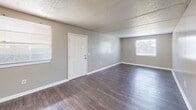 Located at 2401 Jammes Rd in Jacksonville, Florida, this single-floor, 2-bedroom, 1-bathroom residence offers a practical and comfortable layout. The interior is finished with consistent wood-style laminate flooring throughout, complemented by neutral gray walls and white baseboards that create a clean, cohesive look. Textured ceilings add a classic touch to each room.

The main living area is an open, well-lit space featuring two windows that allow ample natural light and views of the surrounding area. A six-panel entry door anchors the front of the space. Both bedrooms are generously sized, each with windows fitted with blinds for privacy and natural light control. The primary bedroom includes a louvered bi-fold closet door, while the second bedroom benefits from a dedicated walk-in closet with built-in wire shelving and hanging rods for organized storage.

The bathroom is outfitted with a full tub-and-shower combination featuring white tile surrounds and safety grab bars, along with standard fixtures. A hallway connects the main rooms and includes a utility panel. The kitchen area, visible in the floor plan, rounds out the functional layout of this straightforward and well-maintained residence.