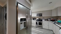 Located at 1539 Beloit Ave in the heart of West Los Angeles, this thoughtfully designed one-bedroom, one-bathroom unit offers a clean, modern aesthetic across a well-utilized single floor. The open-concept layout connects the kitchen, dining, and living areas seamlessly, creating a bright and functional living space.

The kitchen is a standout feature, equipped with full-size stainless steel appliances including a gas range, over-the-range microwave, side-by-side refrigerator with ice and water dispenser, and dishwasher. Light gray flat-panel cabinetry and neutral countertops complete the contemporary look, complemented by a tiled backsplash and a peninsula that opens to the living and dining area.

The living area features wood-look luxury vinyl flooring and recessed lighting, lending a warm and modern feel. A hallway connects the main living space to the private bedroom, which is carpeted and features a window with views of surrounding greenery, providing a quiet retreat. A dedicated closet provides additional storage.

The bathroom is finished with large-format white wall tiles and includes a soaking tub with a frameless glass shower enclosure and polished chrome fixtures, offering a clean and spa-like atmosphere. Throughout the unit, crisp white walls, recessed lighting, and consistent finishes create a cohesive and contemporary living environment.