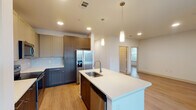 This well-appointed single-story home in Humble, Texas offers a thoughtfully designed open-concept layout across two bedrooms and two full bathrooms. The modern kitchen is a standout feature, showcasing two-tone cabinetry in walnut and taupe finishes, crisp white quartz countertops, stainless steel appliances including a French door refrigerator with ice maker, a built-in microwave, and a dishwasher. A central island with an undermount sink and pendant lighting above serves as both a functional workspace and a natural gathering point, flowing seamlessly into the living and dining areas. Wood-look plank flooring runs throughout the main living spaces, adding warmth and continuity. The bedrooms are bright and airy, benefiting from large windows with blinds and ceiling fans that invite natural light and airflow. Both bathrooms are finished with subway tile tub-shower surrounds, chrome fixtures, and warm wood-toned vanity cabinetry. A dedicated laundry room accommodates a full-size washer and dryer with a shelving unit above. The home also includes an attached single-car garage with an automatic opener, offering convenient and secure parking. Recessed lighting throughout and a clean, neutral palette give the space a fresh, contemporary feel.