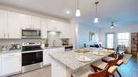 Located at 50 Palma Vista Way in Saint Augustine, FL, this single-floor residence offers 2 bedrooms, 2 bathrooms, a dedicated office, and in-unit laundry within a thoughtfully designed layout. The open-concept kitchen is a standout feature, showcasing white shaker cabinetry, granite countertops, a subway tile backsplash, stainless steel appliances, and a large center island with pendant lighting — ideal for both meal preparation and casual dining. The kitchen flows seamlessly into the living area, which features wood-style flooring, a ceiling fan, and a window that brings in natural light. The primary bedroom is generously sized with plush carpeting, a ceiling fan, and easy access to the hallway and closet. The second bedroom also features carpet, a ceiling fan, and a window with outdoor views. The dedicated office space is bright and versatile, with carpet flooring, a ceiling fan, and a window. Both bathrooms are finished with granite-topped vanities, white cabinetry, and wood-style flooring. The in-unit laundry room houses a full-size washer and dryer with overhead shelving for added storage. Clean white walls and consistent finishes create a cohesive, modern ambiance throughout.
