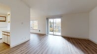 This single-floor unit offers a thoughtfully arranged layout with a clean, neutral aesthetic throughout. The open living area is finished with light wood-style flooring and features large sliding glass doors leading to a balcony, allowing generous natural light and views of surrounding greenery. An additional window further brightens the space, and a ceiling fan adds functional comfort.

The kitchen is efficiently designed in a U-shaped configuration, featuring white cabinetry with warm wood-tone trim, ample upper and lower storage, a dishwasher, electric range, refrigerator, and a double-basin sink. A breakfast bar provides additional workspace and casual dining potential.

The bedrooms are carpeted for comfort and each includes a wide window framing pleasant outdoor views of trees and landscaping, contributing to a calm, natural atmosphere. One bathroom features a full tub-shower combination with a curved curtain rod, wood-trimmed vanity, and light wood-style flooring. A second vanity area with generous counter space and cabinetry is accessible separately, offering added convenience.

The entry area provides a welcoming transition into the main living spaces, finished with the same wood-style flooring that runs consistently through the common areas. Overall, the unit presents a practical and well-lit living environment with a cohesive, understated design.