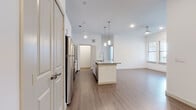 This single-floor residence is designed with a clean, contemporary aesthetic, featuring white walls, wood-look plank flooring, and an open layout that promotes a sense of spaciousness throughout. The kitchen serves as the centerpiece, showcasing white shaker-style cabinetry extending to the ceiling, granite countertops, a white subway tile backsplash, and a full suite of stainless steel appliances including a refrigerator, range, and microwave. A central island with a granite surface and undermount sink provides additional workspace and is illuminated by modern pendant lights overhead.

The open-concept design allows the kitchen to flow seamlessly into the living area, which is equipped with a ceiling fan and receives natural light through windows fitted with horizontal blinds. A dedicated office nook features a built-in granite-topped desk and open shelving, offering a functional workspace.

The bedrooms are bright and well-proportioned, each with wood-look flooring, ceiling fans, and natural light. The bathrooms are finished to a high standard, with marble-look tile on the floors and walls. One bathroom features a glass-enclosed walk-in shower, while another includes a soaking tub with brushed gold fixtures, adding an upscale touch to the overall design.