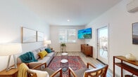 This single-floor residence offers a thoughtfully designed layout with clean, contemporary finishes and a warm, inviting ambiance. The living room serves as the heart of the home, showcasing light-toned hardwood-style flooring, crisp white walls, and abundant natural light streaming through white-slatted blinds. A wall-mounted flat-screen TV, mid-century inspired seating, and a vibrant area rug lend the space a stylish yet comfortable character. A glass-panel door opens directly onto a private balcony, extending the living area outdoors. The kitchen is well-appointed with rich dark wood cabinetry, granite-style countertops, stainless steel appliances including a range, microwave, dishwasher, and refrigerator, and a dedicated dining area with a glass-top table. An in-unit washer and dryer add everyday convenience. The bedroom is a serene retreat, featuring the same light hardwood-style flooring, soft neutral tones, and warm ambient lighting. The bathroom is finished with a dark wood vanity, a large mirror, white countertops, and a full tub-shower combination, maintaining the cohesive modern aesthetic found throughout the home. Every room reflects a balance of functionality and contemporary design.