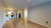 This single-floor unit is designed with a clean, contemporary aesthetic and a practical open-concept layout. The living area is generously proportioned, featuring light wood-style luxury vinyl plank flooring, neutral gray walls, and recessed lighting that creates a bright, welcoming atmosphere. A window allows natural light to fill the space, enhancing its airy feel.

The kitchen is well-appointed with white shaker-style cabinetry, a white subway tile backsplash, and a full suite of stainless steel appliances, including a refrigerator, electric range, microwave, and dishwasher. The layout provides ample counter space and storage, making it both functional and visually appealing.

A dedicated bedroom features carpeted flooring and a window with blinds, offering a quieter, comfortable retreat. The bathroom includes a clean, white tub-shower combination with chrome fixtures. A separate laundry area is equipped with a stacked washer and dryer unit alongside wire shelving, adding practical storage and convenience.

Overall, the unit presents a modern, move-in-ready interior with consistent finishes, efficient use of space, and thoughtful amenities throughout.