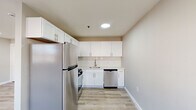 This 2-bedroom, 1-bathroom unit offers a clean, modern aesthetic across a single floor with a well-considered layout. Light-toned hardwood-style flooring runs throughout all rooms, lending a cohesive and contemporary feel to the space.

The living room is bright and open, featuring recessed lighting and a window with natural light, along with a wall-mounted HVAC unit and baseboard heating for year-round comfort. The kitchen is efficiently designed with white shaker-style cabinetry, a white subway tile backsplash, light stone countertops, and stainless steel appliances including a refrigerator, gas range, and dishwasher. Recessed lighting overhead keeps the space bright and functional.

The spacious primary bedroom is a standout, offering generous room for furnishings, multiple windows that invite natural light and outdoor views, and both baseboard heating and a wall HVAC unit. The second bedroom is also comfortably sized with a window and baseboard heating. Both bedrooms have access to dedicated closet storage.

The bathroom is neatly finished with large-format slate-toned tile flooring, a white vanity, and a tub-shower combination with tiled surround. A central hallway connects all rooms, creating a logical and easy-to-navigate flow throughout the unit.