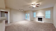 This 2-bedroom, 2-bathroom single-floor residence offers a thoughtfully designed layout across a generous footprint. The open living room serves as the heart of the home, featuring plush carpeting, a ceiling fan with light fixture, track lighting, and a classic wood-burning fireplace with a white mantel surround. French doors and multiple windows flood the space with natural light and provide outdoor views, while a pass-through opening connects seamlessly to the kitchen. The kitchen is well-equipped with rich, warm-toned cabinetry, light stone-finish countertops, wood-look flooring, and stainless steel appliances including a range and over-the-range microwave. A utility room is conveniently accessible from the kitchen. Both bedrooms are carpeted and include ceiling fans, with the primary bedroom offering a notably spacious layout and two windows with outdoor views. Each bedroom is served by a dedicated bathroom, both featuring wood-look tile flooring, a tub-shower combination, rich cabinetry, and brushed nickel hardware. Additional storage is provided by two closets, including one with a built-in wire shelving system. A hallway connects the private areas of the home, completing this functional and comfortable floor plan.