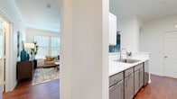 This single-floor residence showcases a thoughtfully designed open-concept layout that seamlessly connects its living spaces. Rich hardwood flooring flows throughout the main areas, complemented by elegant crown molding, arched doorways, and ceiling fans in every room — details that lend a cohesive, polished character to the home.

The living room is bright and welcoming, featuring large windows with plantation-style blinds that bathe the space in natural light. It connects effortlessly to the dining area, which is distinguished by track lighting, a vaulted accent wall, and floor-to-ceiling vertical blinds offering privacy and style.

The kitchen is well-equipped with two-tone cabinetry — white uppers paired with gray lowers — light quartz countertops, stainless steel appliances, and a breakfast bar with bar seating, making it equally functional for everyday cooking and casual entertaining.

The bedrooms are carpeted for comfort, each featuring ceiling fans and generous natural light. One room functions as a dedicated home office or flex space, complete with built-in shelving nearby in the living area. The primary bedroom includes a built-in desk nook and convenient arched hallway access.

Throughout the home, built-in display shelves, neutral tones, and consistent architectural details — including arched passages — create a harmonious and inviting living environment.